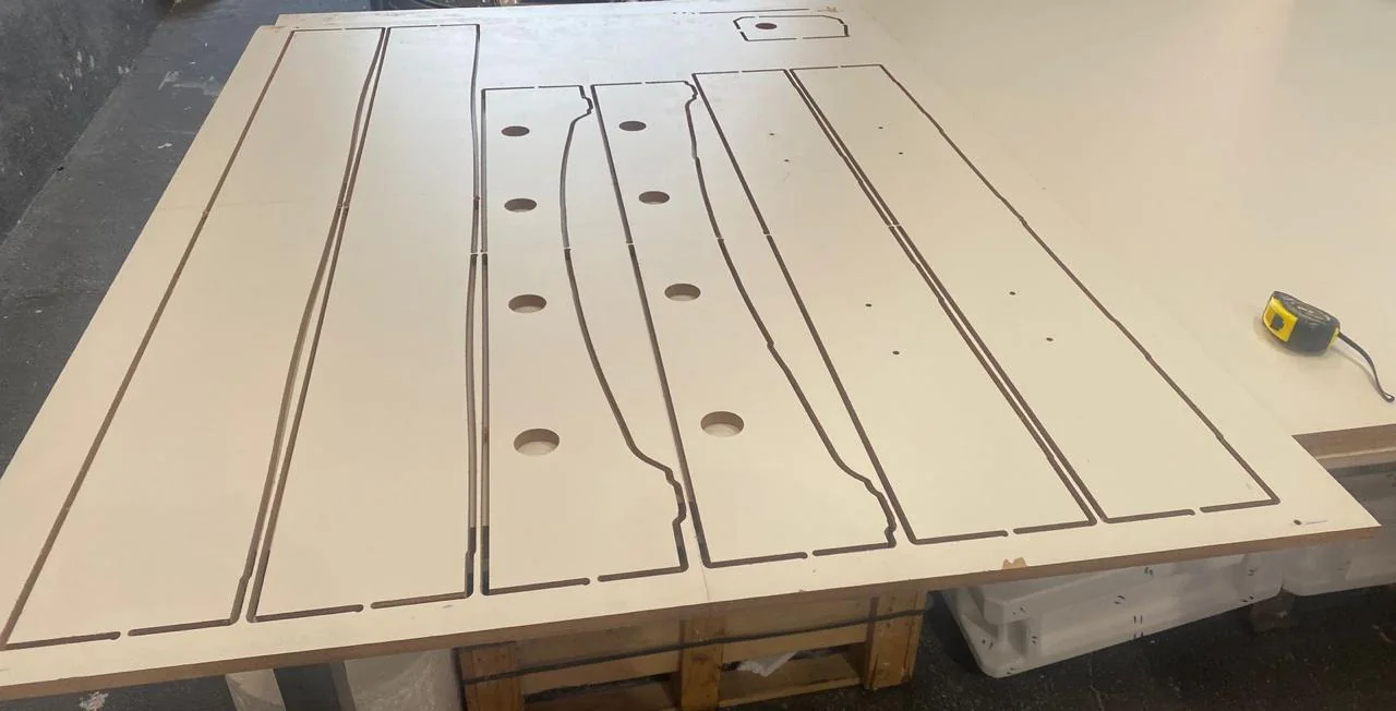 Chapa de MDF com perfis cortados em CNC, sobre a mesa da fresadora