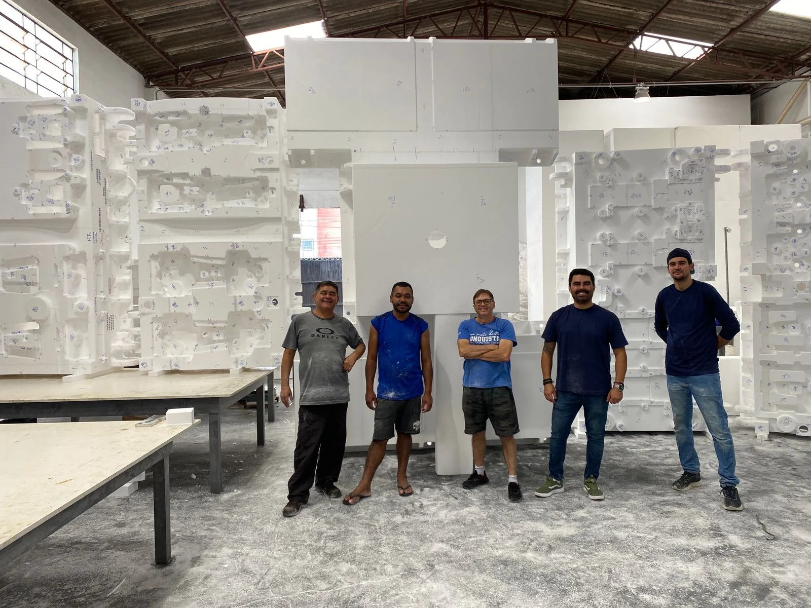 Cinco integrantes da equipe da Moldtec em frente a modelos em EPS de grande porte, no galpão